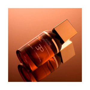 Parfum Ambre Supermassive de Les Eaux Primordiales photographié en ambiance chaude, flacon ambré aux reflets profonds