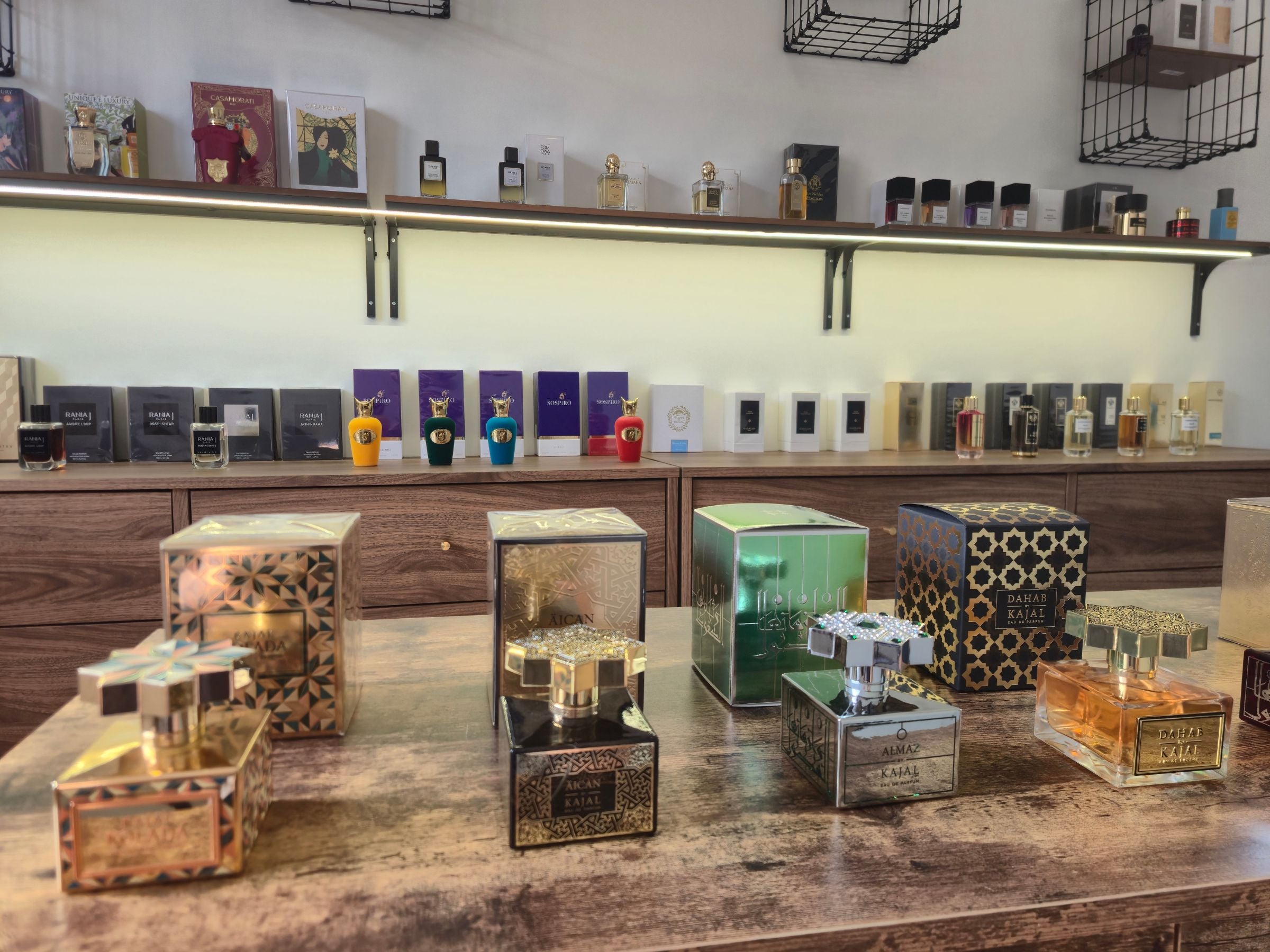 Vue de la boutique privée Artescent à La Garenne-Colombes avec une sélection de parfums de niche de la marque Kajal exposés sur table en bois, et d'autres références sur des étagères en arrière plan