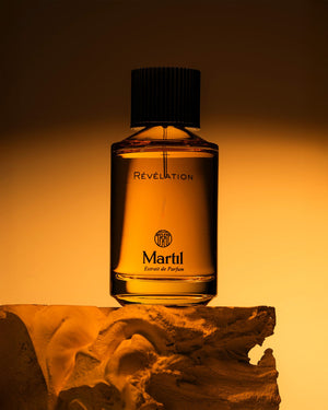 Flacon de Révélation par Martil, extrait de parfum photographié dans une ambiance ambrée et chaleureuse