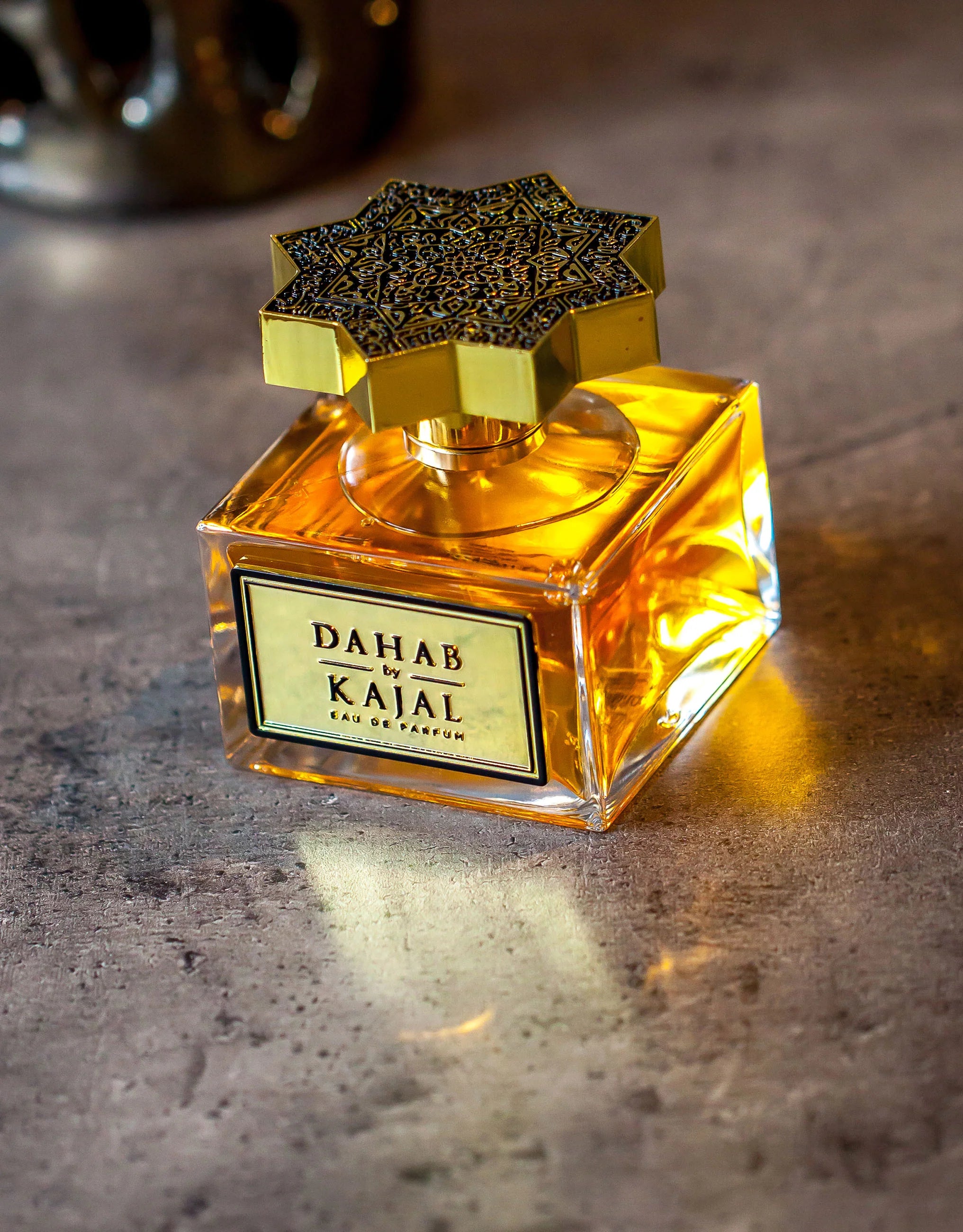 Bouteille de Kajal Dahab posée sur surface brute, lumière chaleureuse révélant la teinte ambrée