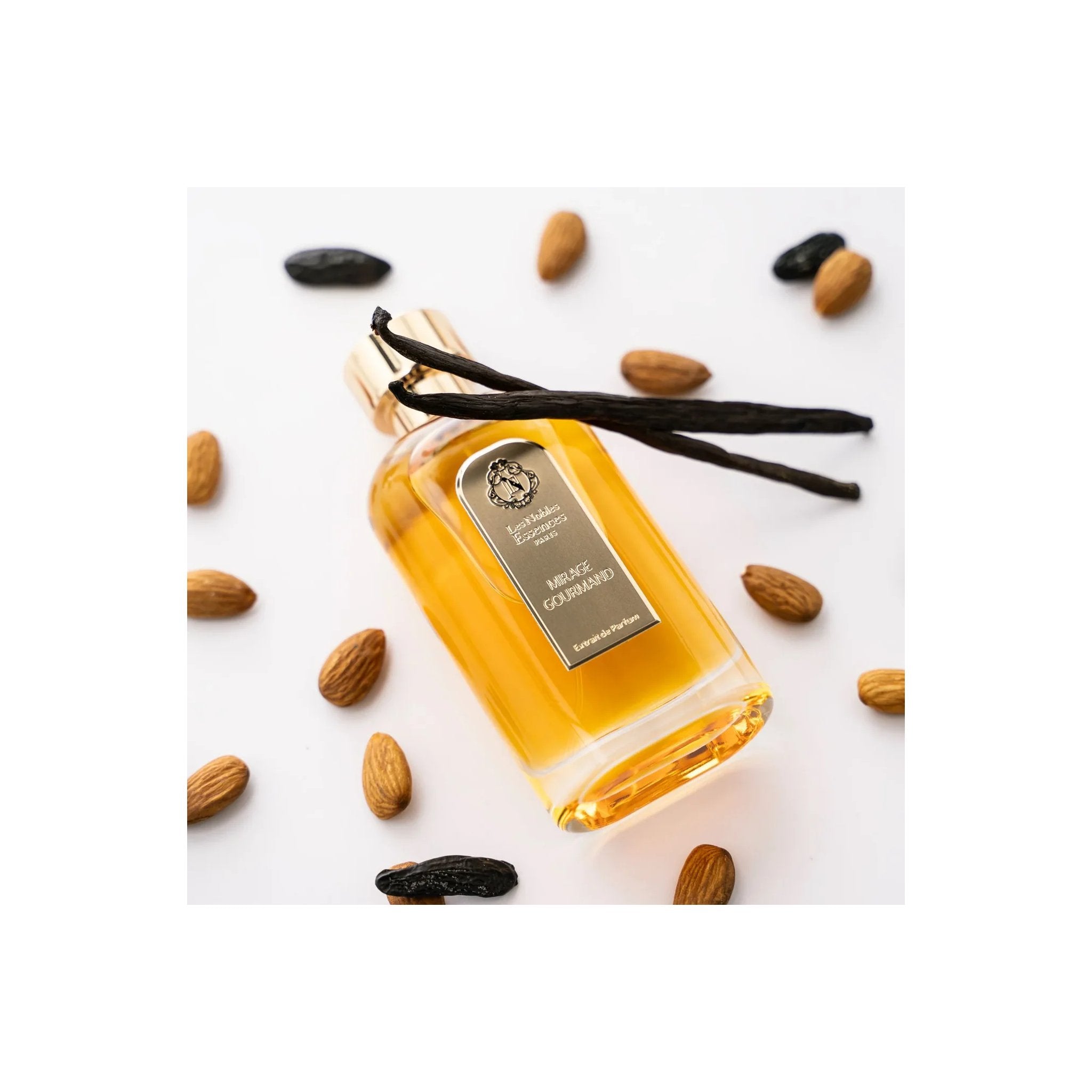 Parfum Mirage Gourmand Les Nobles Essences entouré d’amandes et de gousses de vanille
